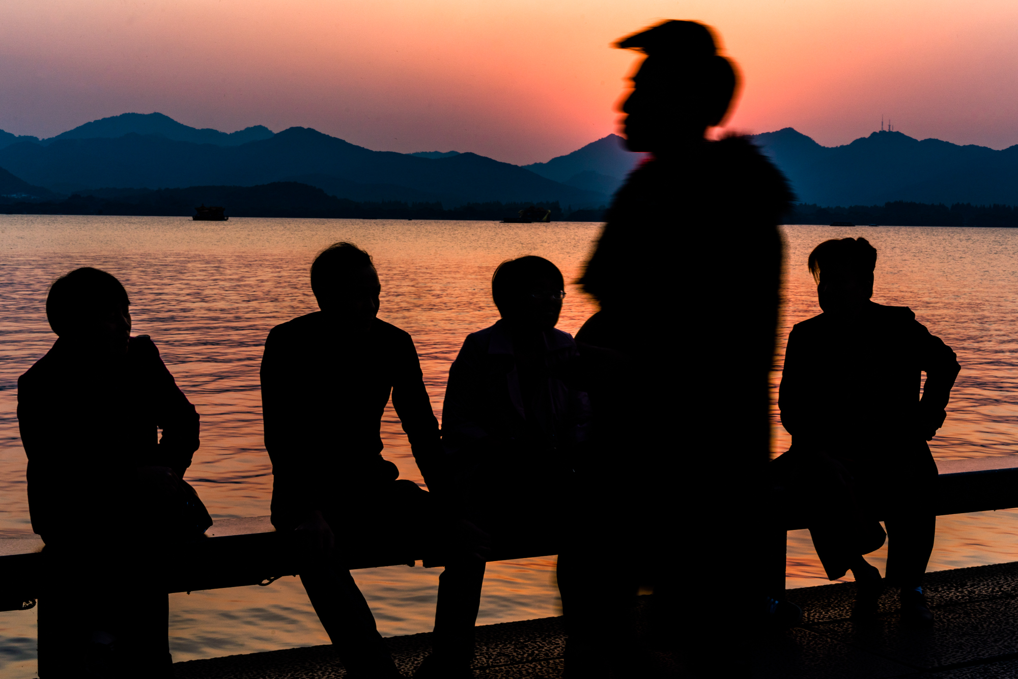 Men gather on a bridge at sunset in Hangzhou, China