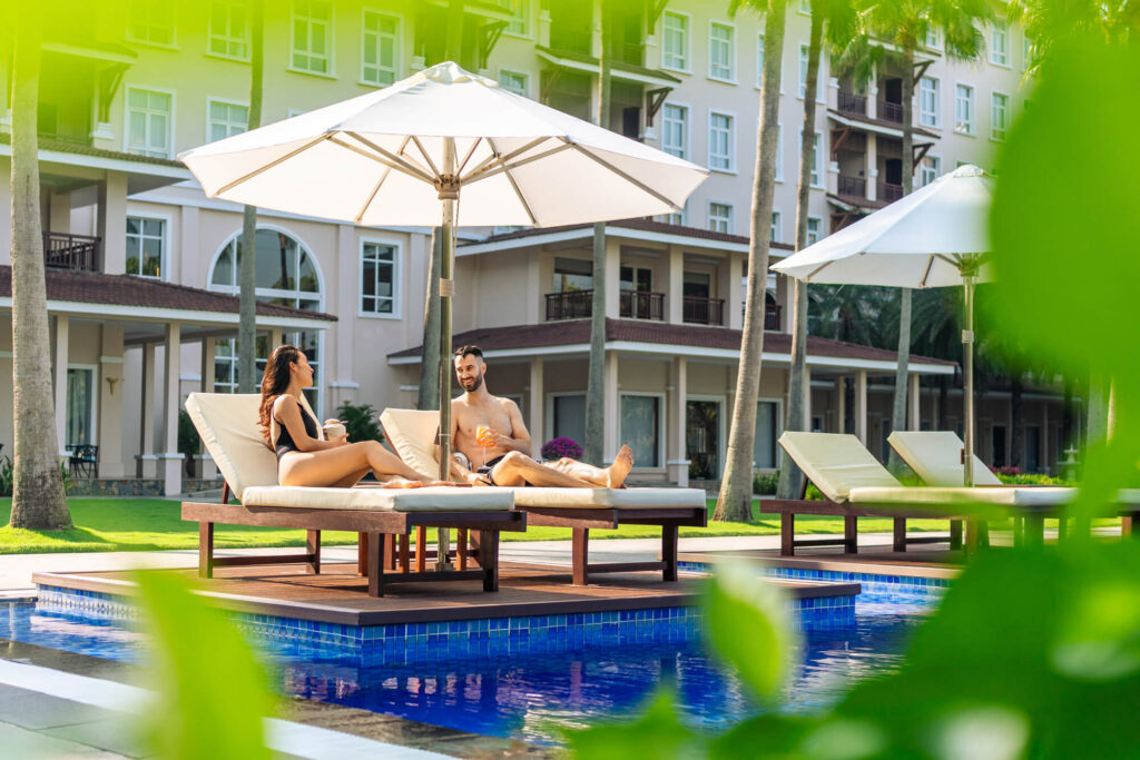 A couple enjoys time with each other poolside at a luxury beach resort in Danang, Vietnam.