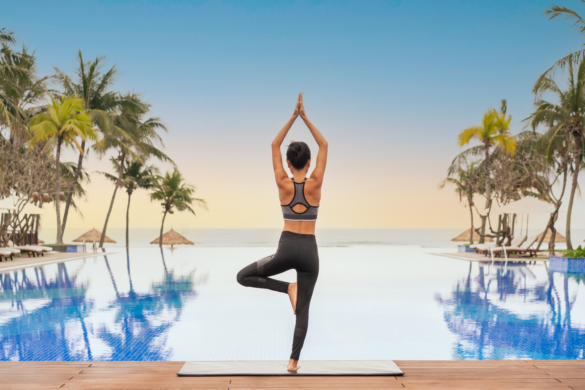 Sunrise yoga by the poolside at a luxury beach resort