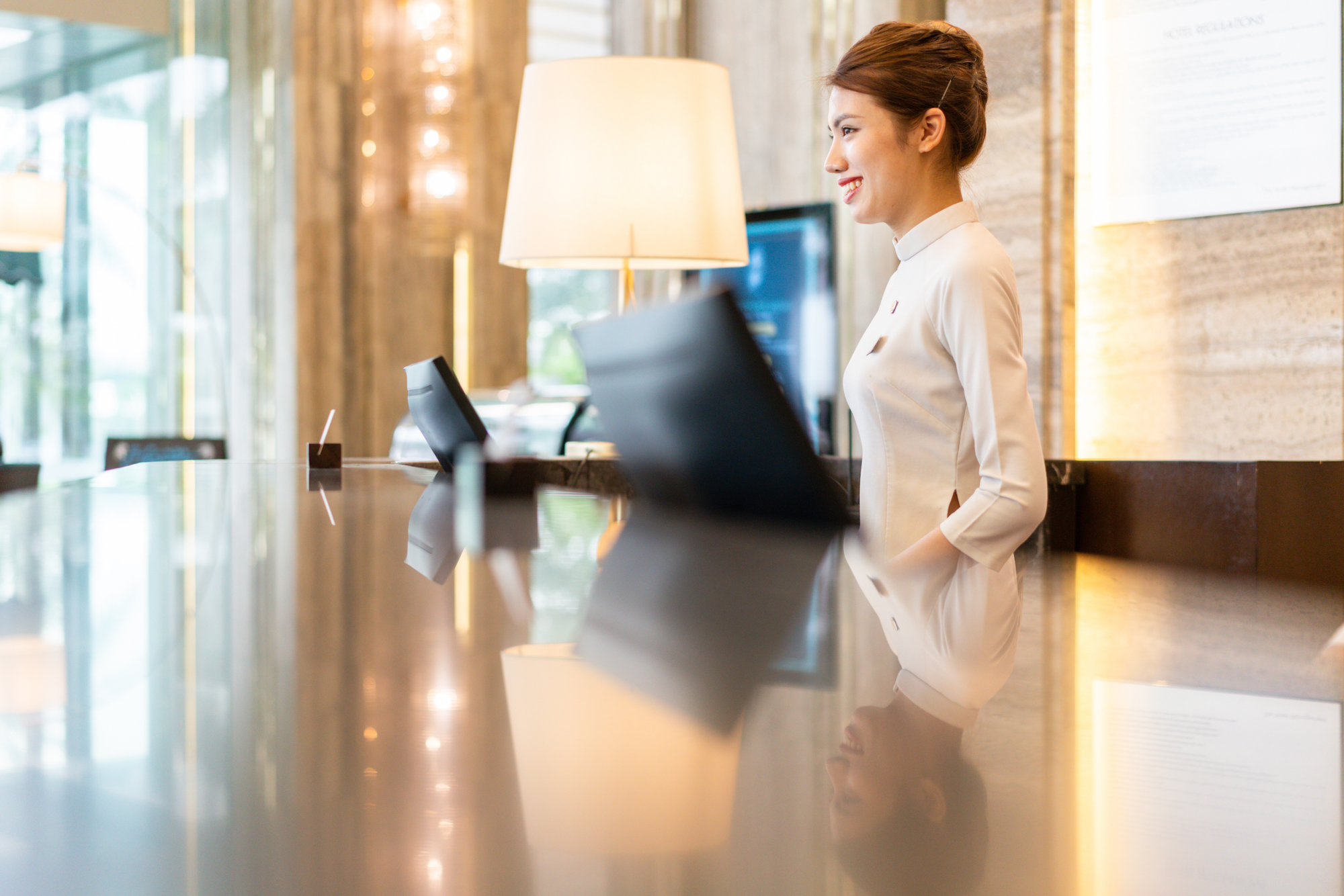 A receptionist offers warm greetings for arriving guests at a luxury hotel in Vietnam.