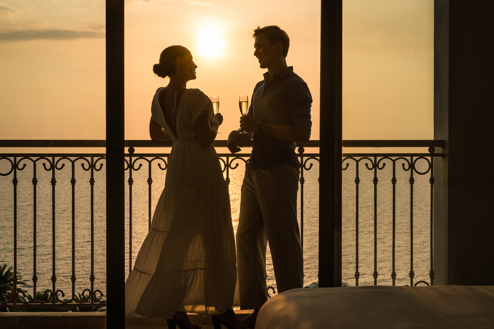A couple enjoys champagne at sunset from the balcony of their room at a luxury resort in Vietnam
