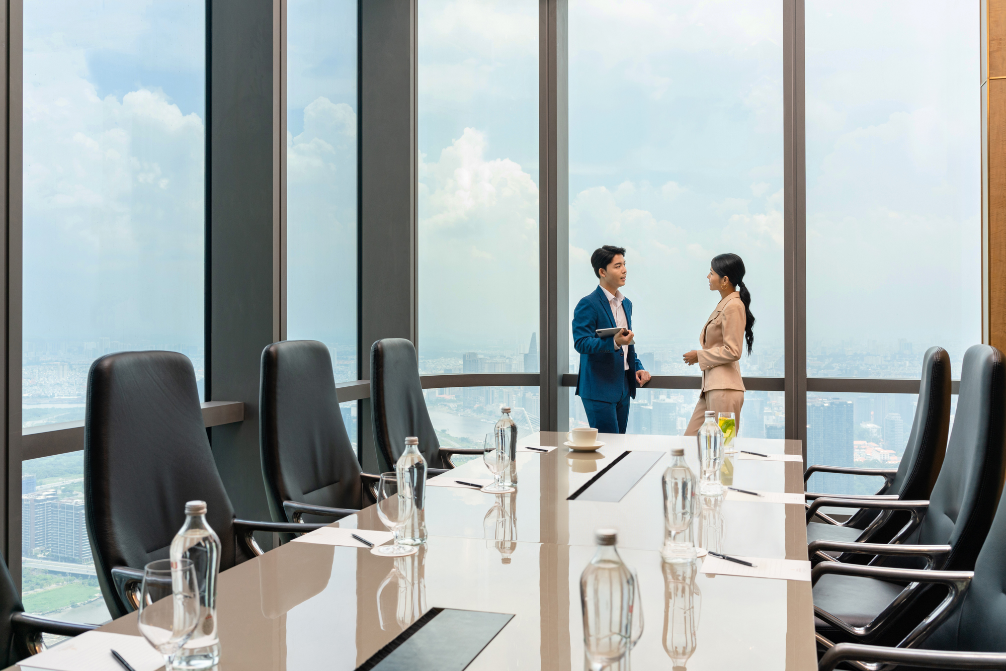 Business associates chat in a meeting room at a hotel with large window views