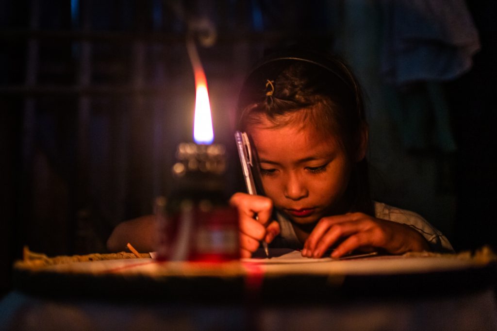 A young girl studies by candle light in her rural home in Ha Nam Province, Vietnam