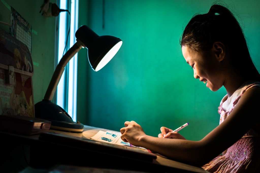 A young girl studies by lamp light in her home in Hanoi, Vietnam