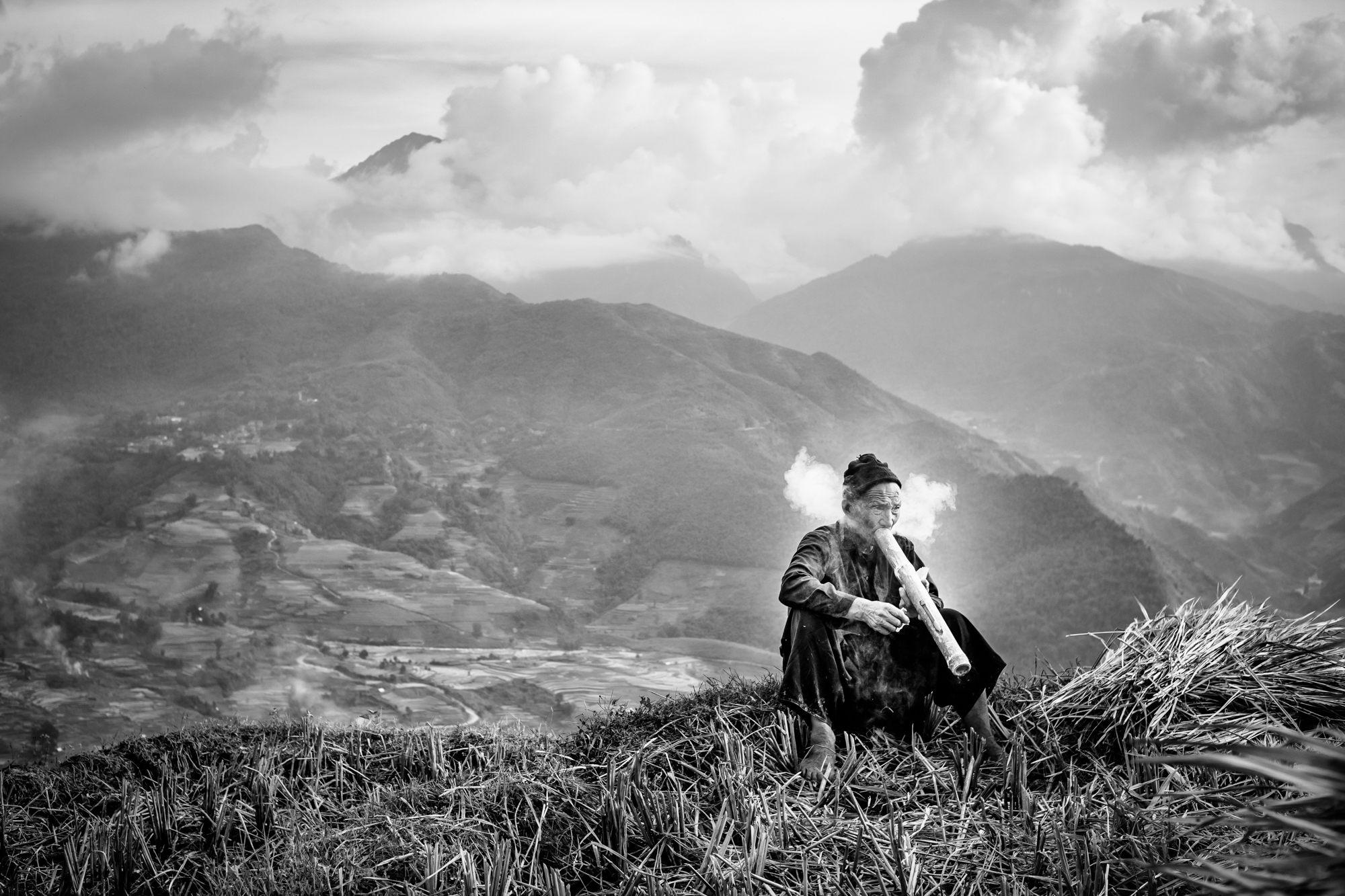 A man stops for a smoke break with a traditional pipe while harvesting rice in northern Vietnam