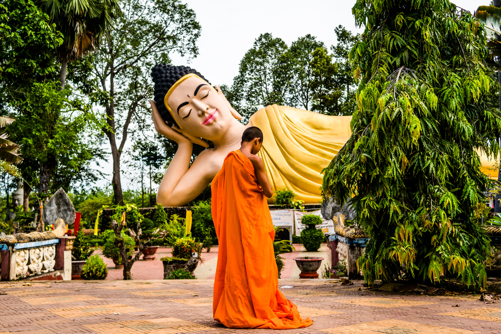 A novice monk passes in front of a large Buddah statue in Prey Nokkor Knung, Cambodia