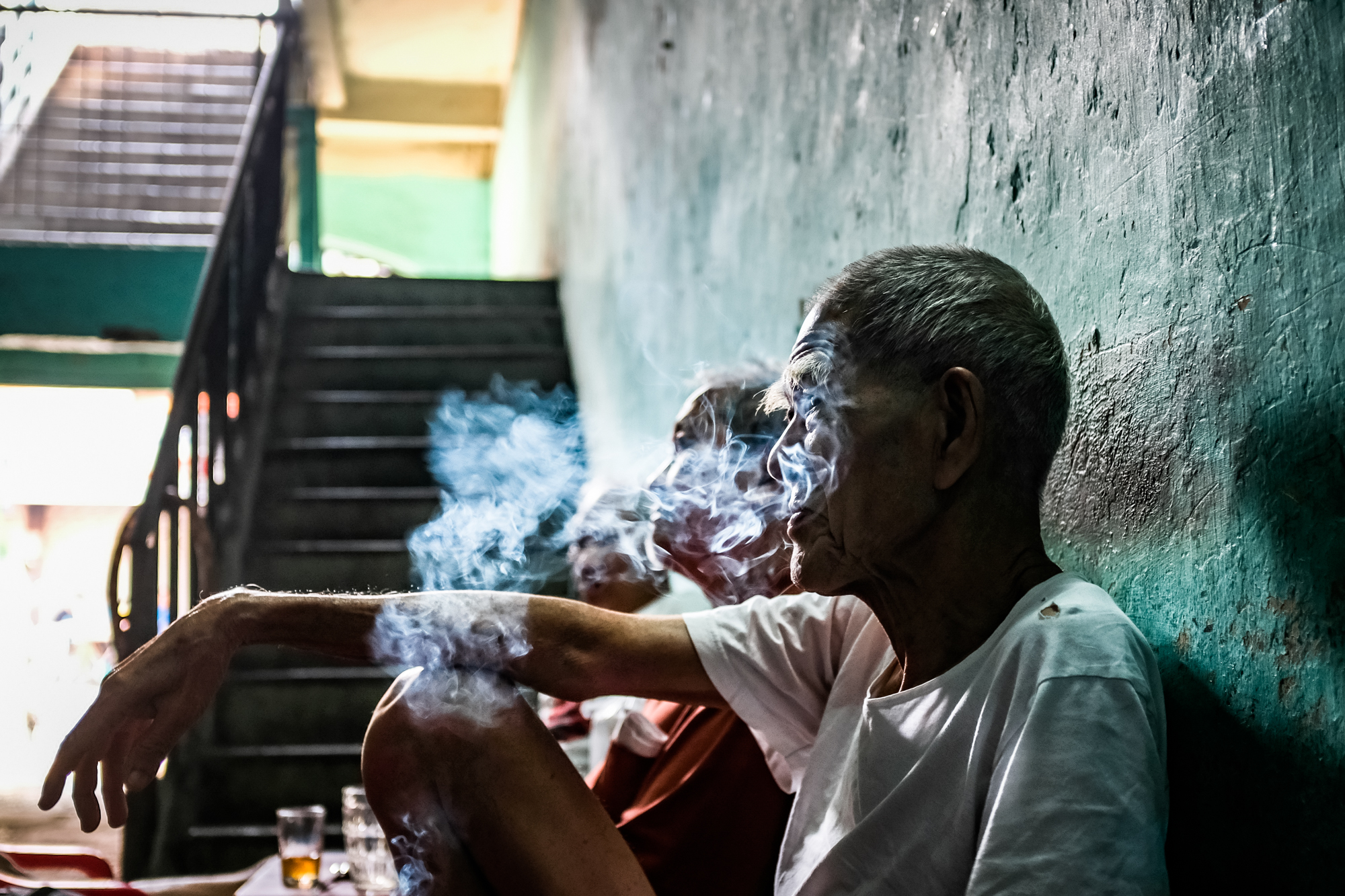 A group of men smoke cigarettes in an historic alley in Chinatown, Ho Chi Minh City, Vietnam